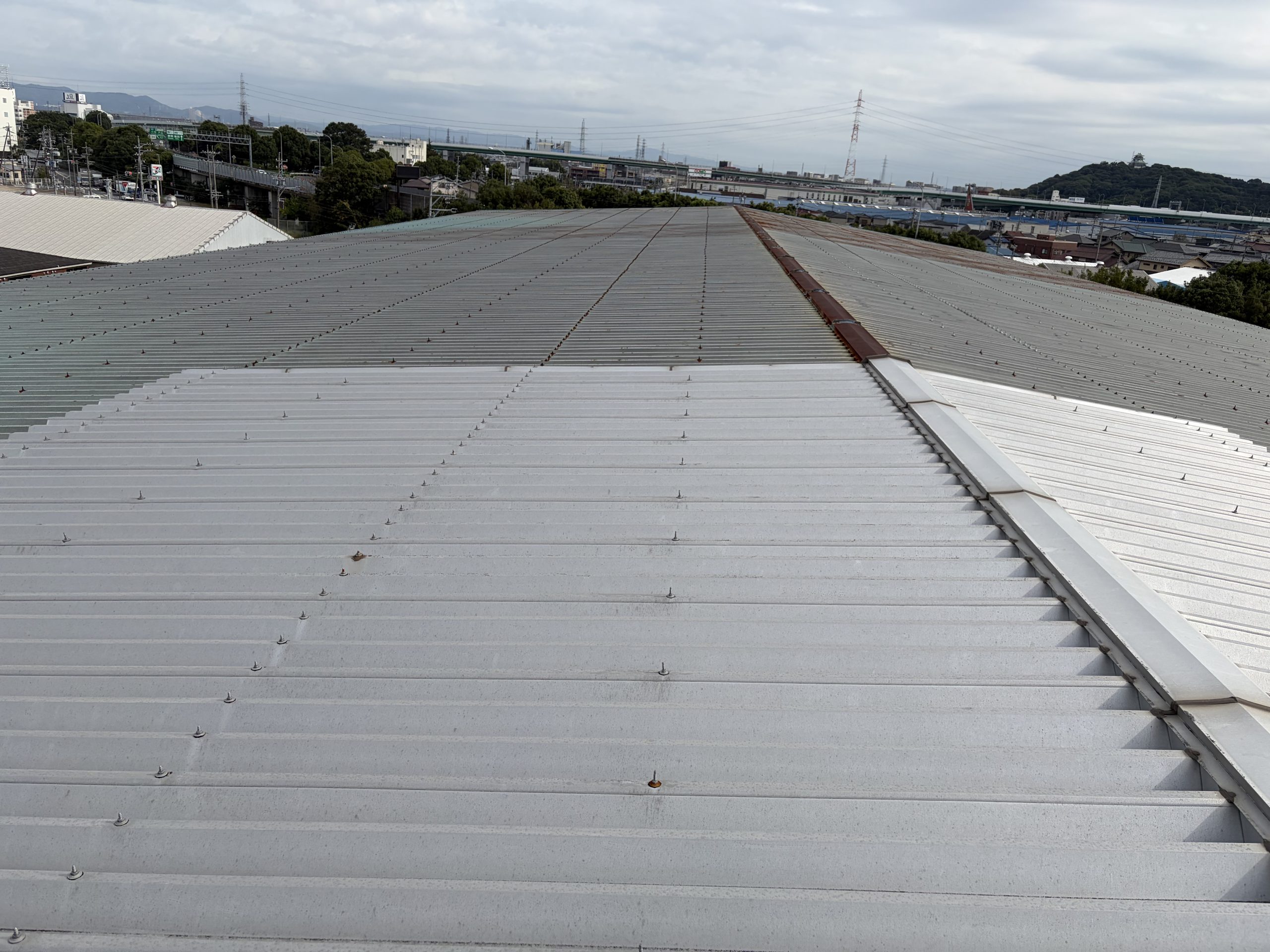 小牧市の大型物流倉庫で雨漏り調査を行った折板屋根。屋根全体に発生した錆と棟板金下の納まり不良を確認し、カバー工法をご提案