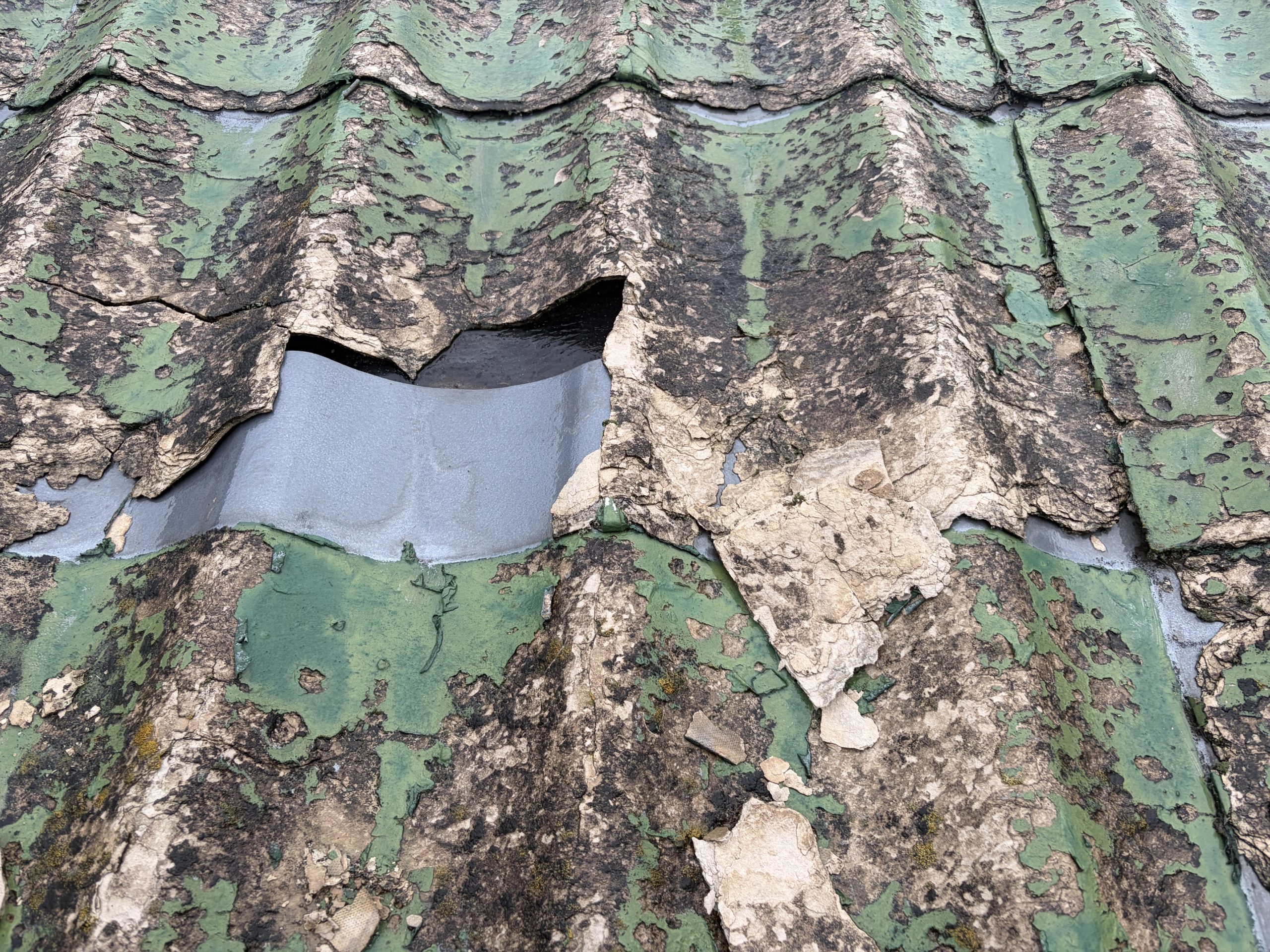 春日井市で雨漏り調査を行ったセキスイかわらUの屋根。屋根材の表面が激しく劣化し、所々に穴が開いている状態