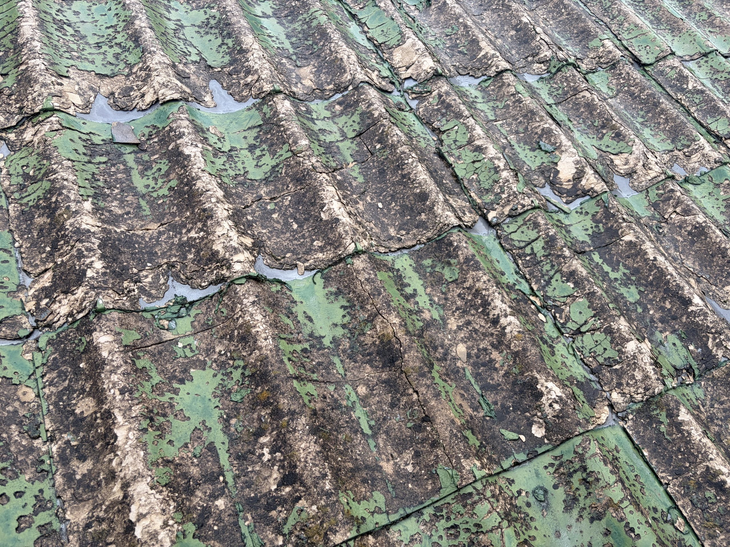 春日井市で雨漏り調査を行ったセキスイかわらUの屋根。屋根材の表面が激しく劣化し、所々に穴が開いている状態